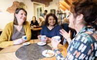 3 vrouwen on een ronde tafel voeren zichtbaar een leuk gesprek